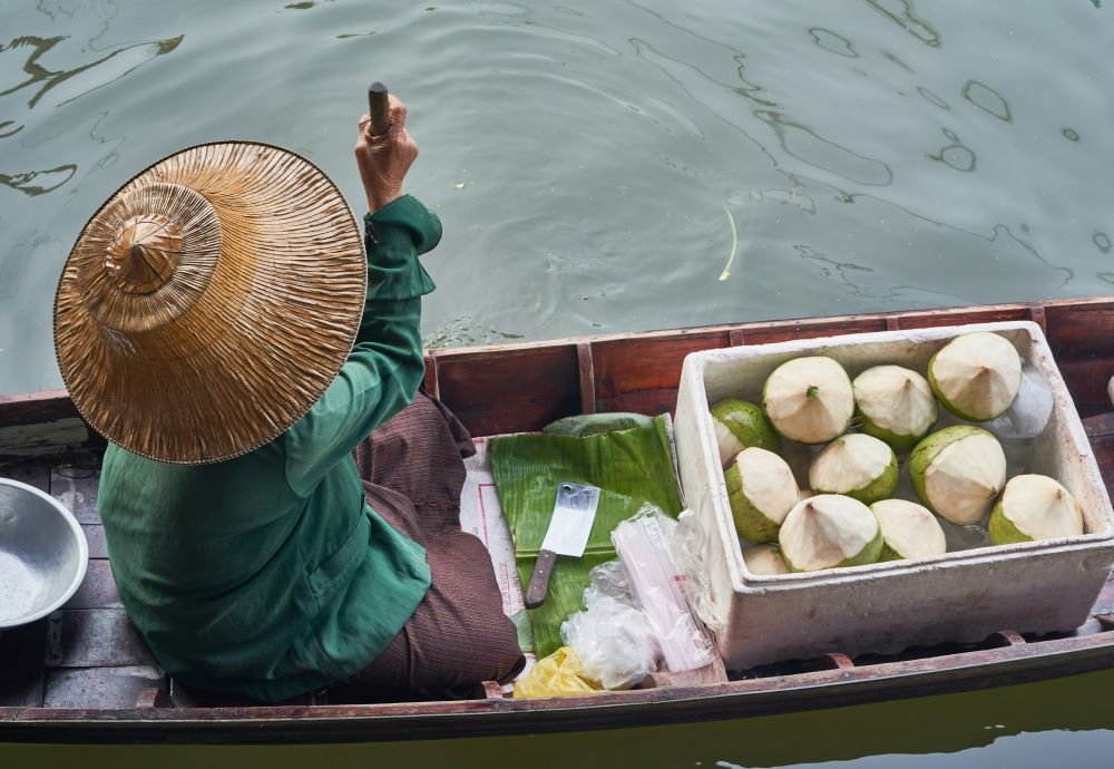 Vendor selling fresh coconuts at Khlong Hae floating market